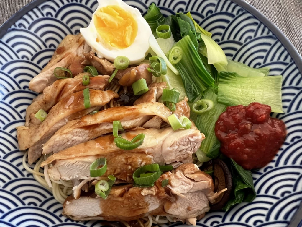 Chinesisches Hähnchen in Sojasauce geschmort mit Nudeln und Blattgemüse