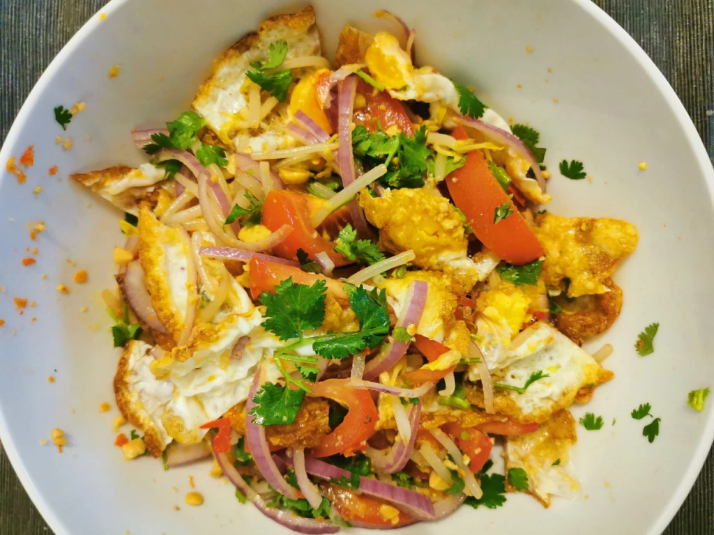 Thai-Salat mit gebratenem Ei, Tomaten, Chili und Koriander